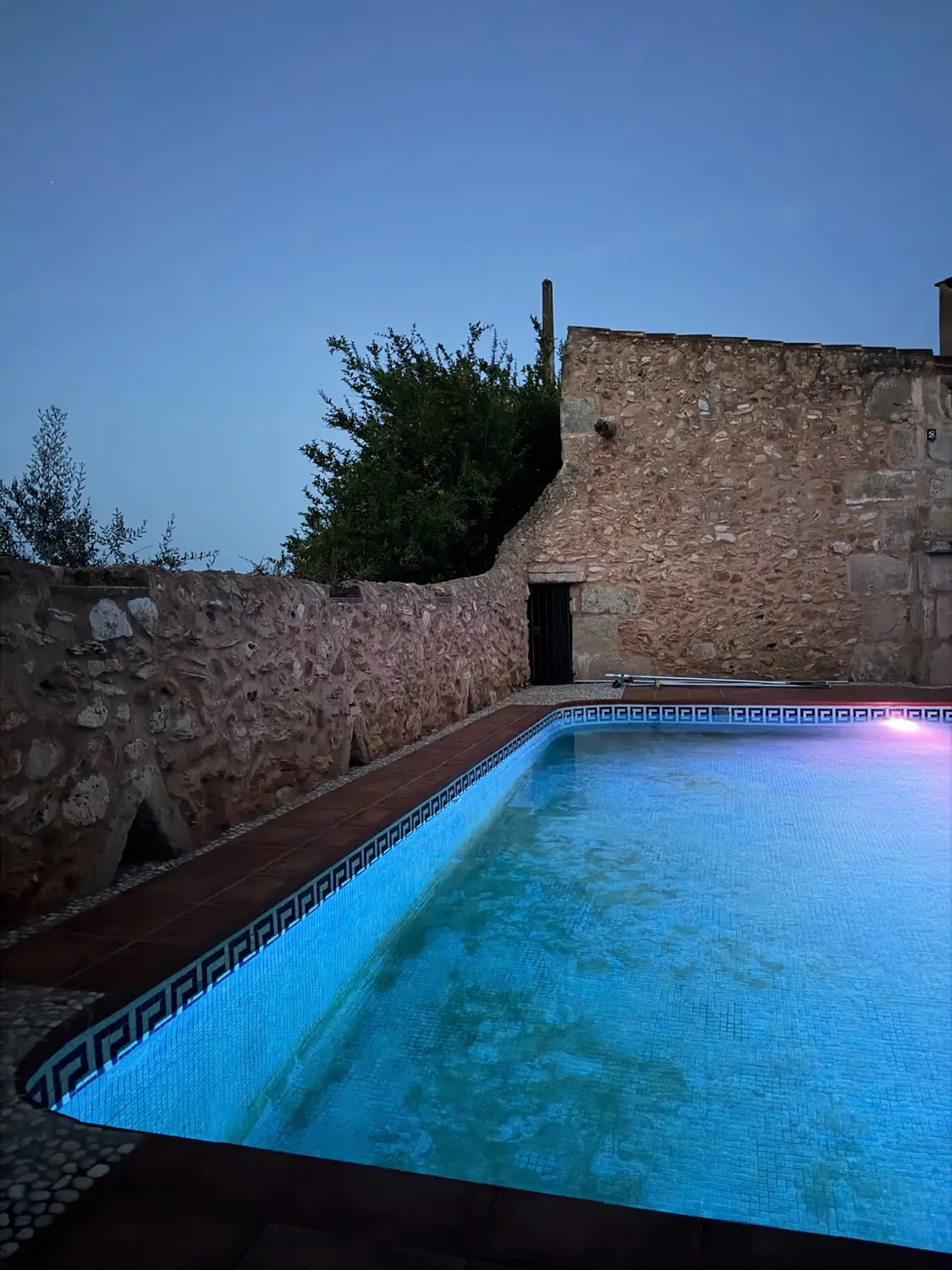 Pool at dusk with the finca lit up